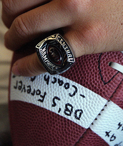 Holding a signed football and wearing a championship ring